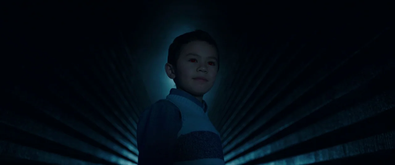 A Wrinkle In Time (2018) movie still: medium — A dark, textured tunnel with repeating horizontal lines recedes into deep shadow. A child with…