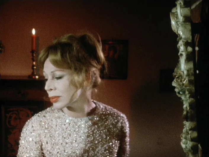 Eika Katappa (1969) movie still: medium — A dimly lit room features a burning candle on a dark mantle. A woman in a sequined top turns her face away…
