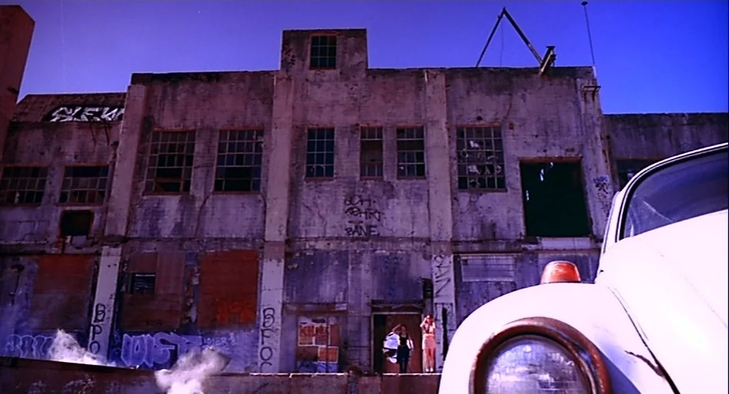Nowhere (1997) movie still: wide — A weathered, multi-story industrial building features graffiti-covered walls and broken, empty window panes. A…