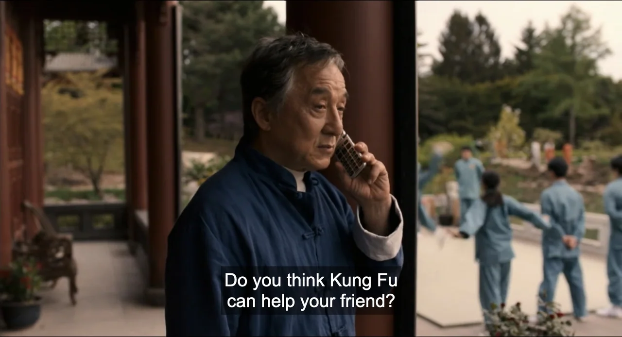 Karate Kid: Legends (2025) movie still: medium — A man stands on a covered outdoor porch of a traditional-style building. He holds a phone to his…