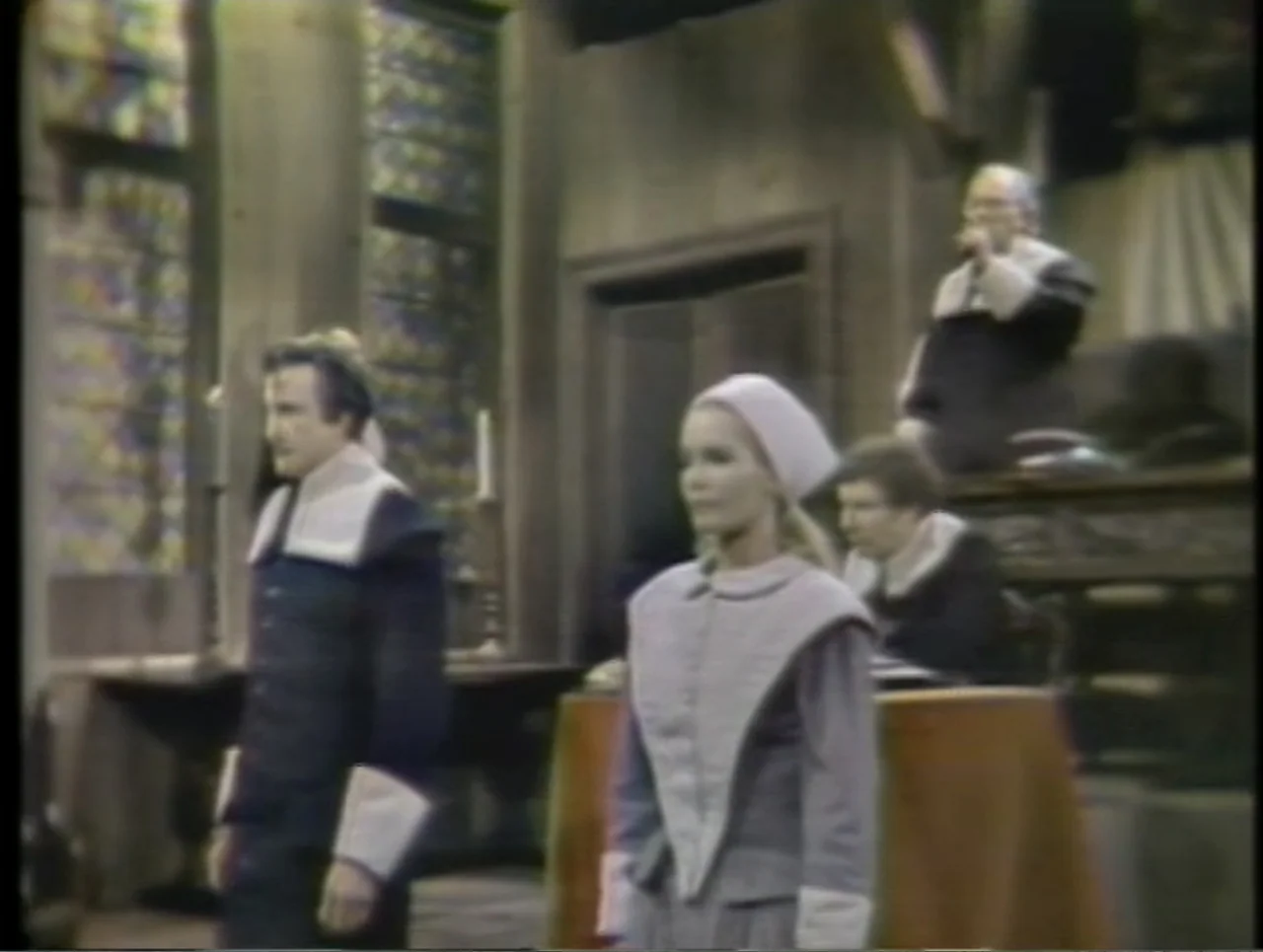 The Crucible (1996) movie still: fullbody — A dark wooden room with stained glass windows features elevated judicial seating in back. A man and a…