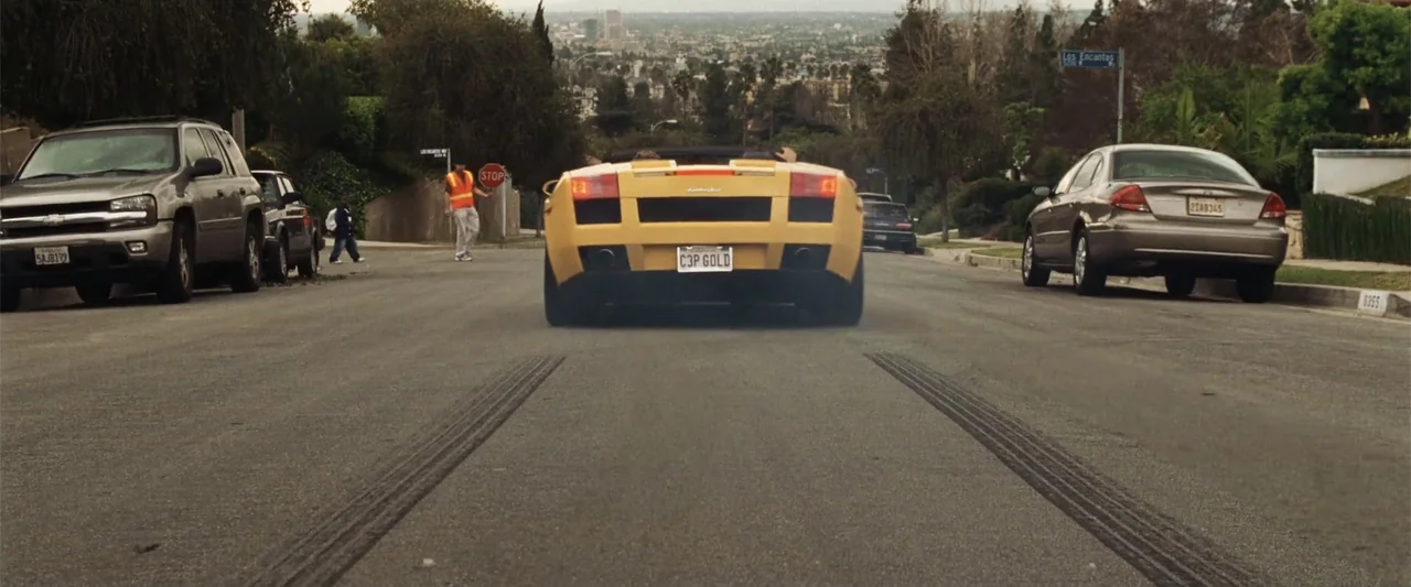 17 Again (2009) movie still: medium — A yellow sports car drives down a residential street with tire marks on asphalt. A worker in an orange safety…