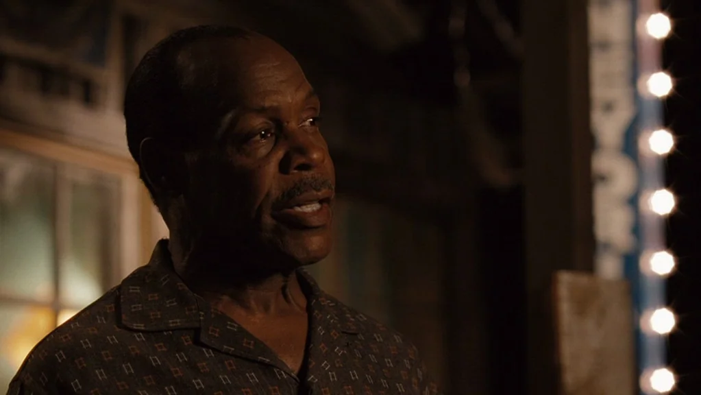Honeydripper (2007) movie still: closeup — An outdoor night setting featuring a dark building exterior with visible light bulbs. An older man stands…