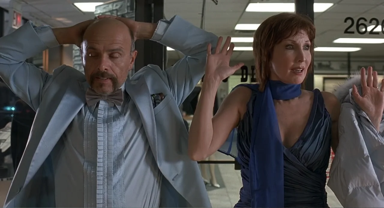 Wedding Daze (2006) movie still: medium — A modern retail store interior with glass doors and a numeric sign visible. A man and a woman stand with…