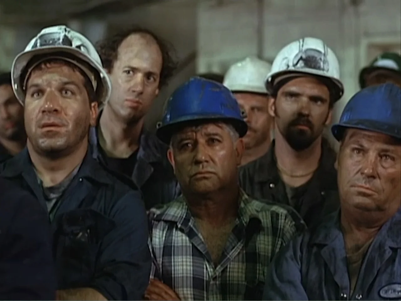 Catch a Falling Star (2000) movie still: medium — A group of industrial laborers in protective gear stands in an indoor facility. They gaze forward…