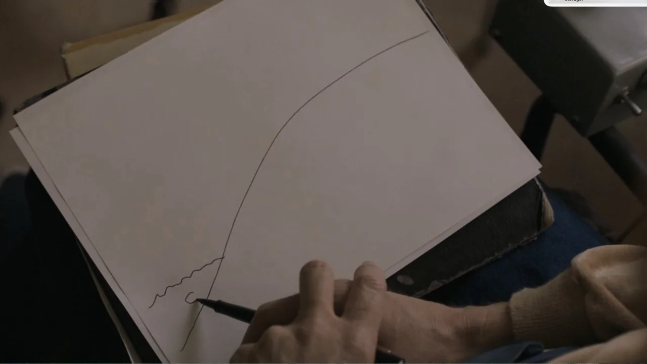 Don't Worry, He Won't Get Far on Foot (2018) movie still: closeup — A close-up of a white sheet of paper resting on a person's lap. The person uses…