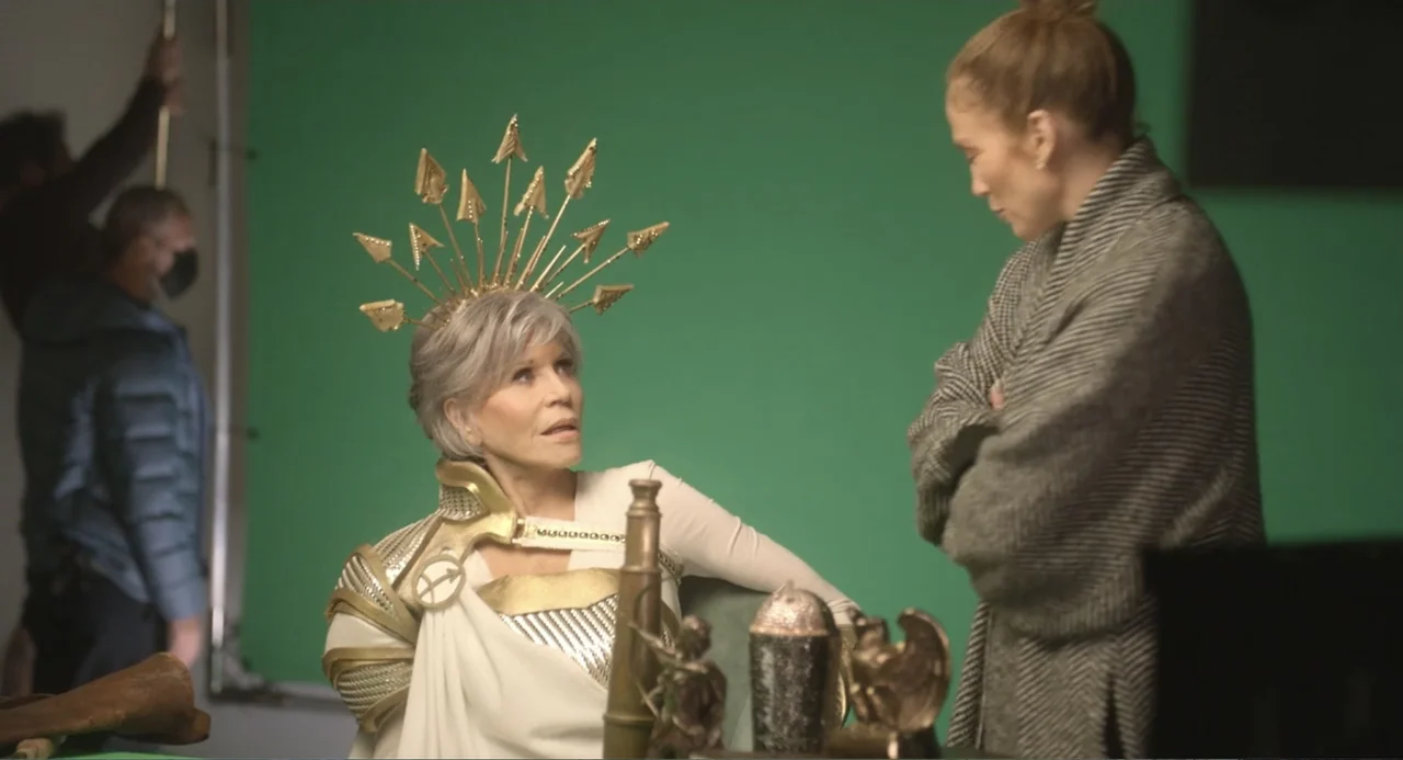 The Greatest Love Story Never Told (2024) movie still: medium — Two women stand in a television production studio against a large green screen…