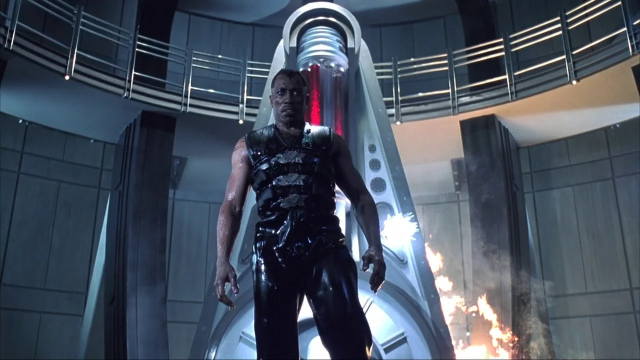 Blade II (2002) movie still: fullbody — A high-tech circular room features metallic wall panels and a glowing red central pillar. A muscular man in…