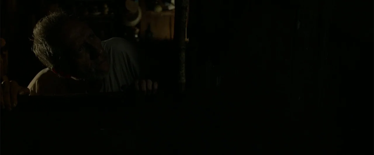 I Dream in Another Language (2017) movie still: medium — A dimly lit interior space features an elderly man emerging from deep shadows. The subject…