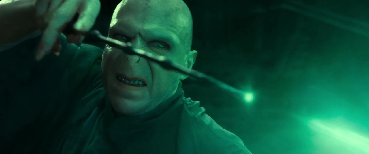 Harry Potter & The Deathly Hallows Part 2 (2011) movie still: closeup — A dark, blurred outdoor space is illuminated by a strong, singular green…