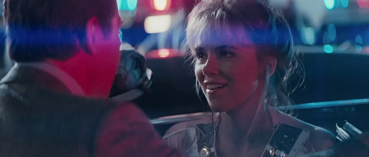 Thelma & Louise (1991) movie still: medium — Two individuals sit inside a dark vehicle at night surrounded by blurred urban lights. A woman faces…