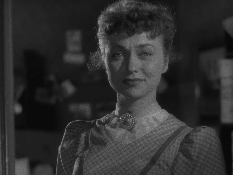 Sawdust and Tinsel (1953) movie still: closeup — A dimly lit room provides the backdrop for a woman in period clothing. The woman is positioned…