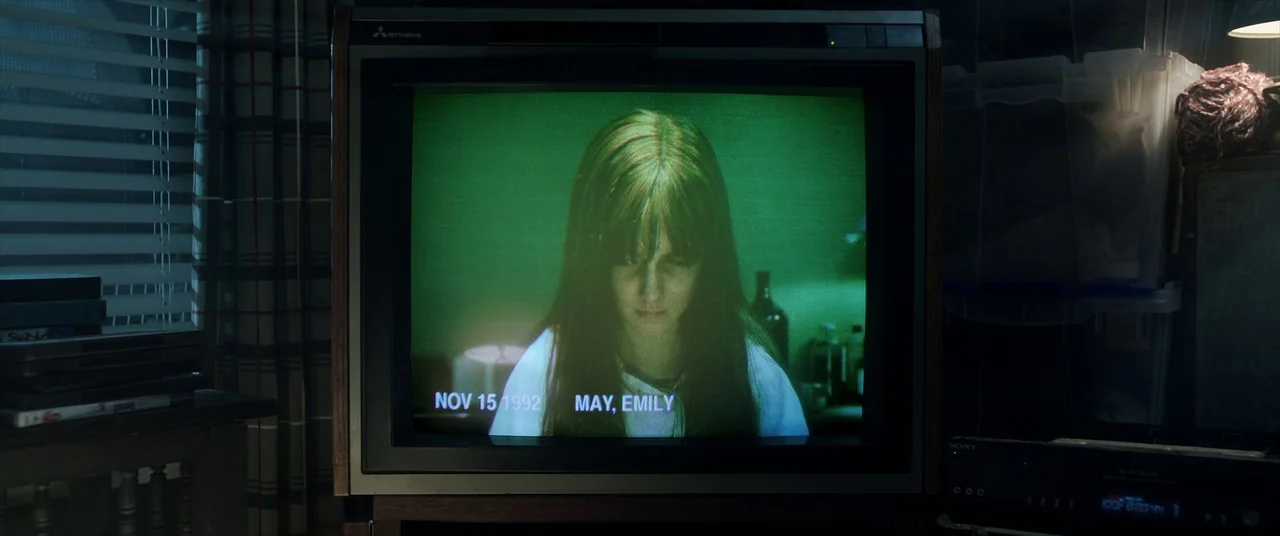 Malignant (2021) movie still: medium — A vintage 1990s cathode ray television displays a green-tinted recording of a young woman. The screen overlay…