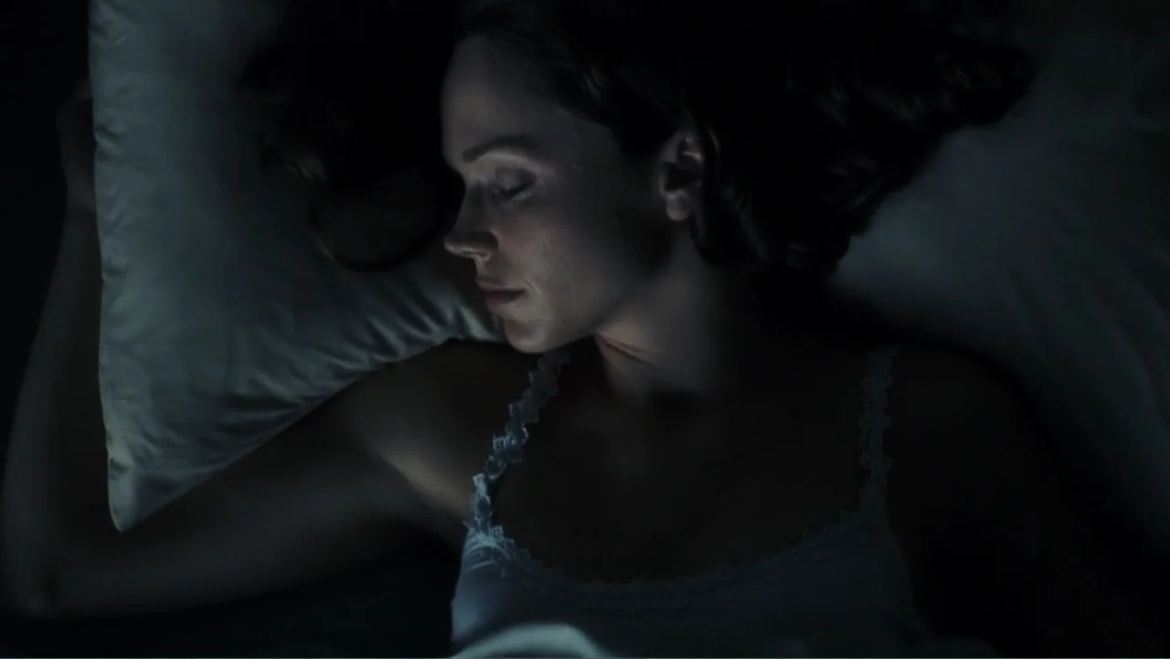 A.I. Artificial Intelligence (2001) movie still: closeup — A dark bedroom interior with the subject resting on a white pillow at night. A woman with…