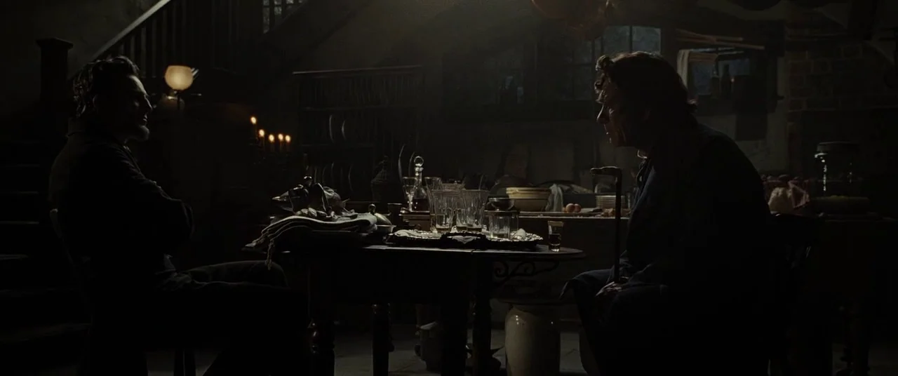 Lincoln (2012) movie still: wide — A dimly lit room with vintage furniture and antique glassware on a dining table. Two men sit at opposite ends of…