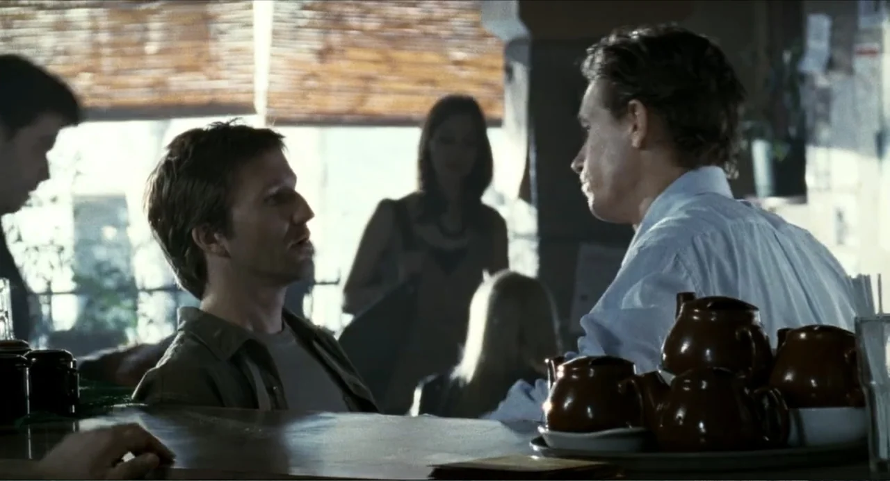 Colin Quinn: Red State, Blue State (2019) movie still: medium — A diner counter with ceramic teapots sits before two men in conversation. The…