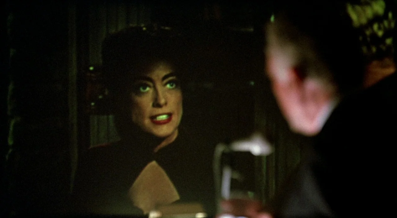 Women on the Verge of a Nervous Breakdown (1988) movie still: closeup — A dark indoor space with a woman visible in the foreground. The woman faces…