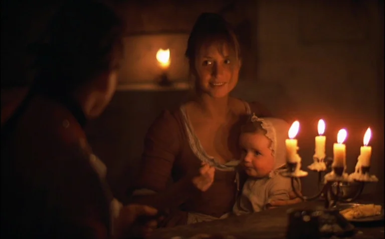 Barry Lyndon (1975) movie still: medium — A dimly lit historical interior features wooden surfaces and dark, obscured walls. A young woman holds an…