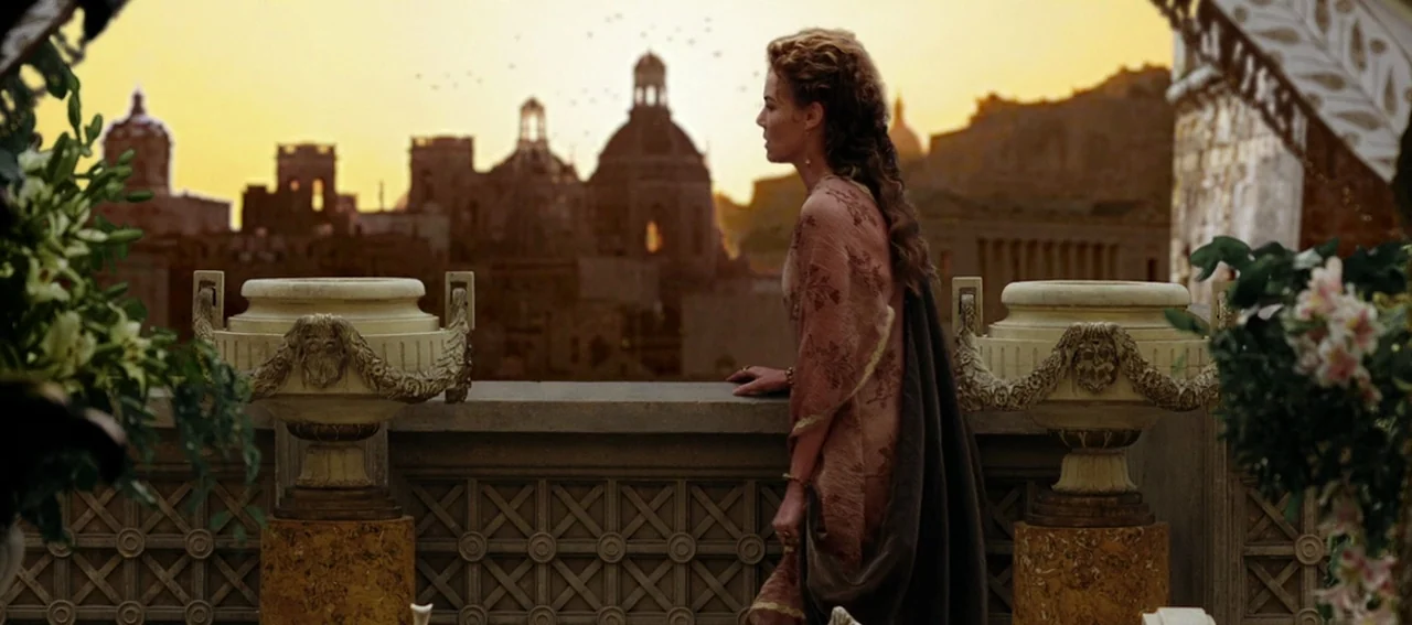 Gladiator (2000) movie still: medium — A stone terrace features ornate pedestals topped with urns and bouquets of white lilies. A woman looks across…