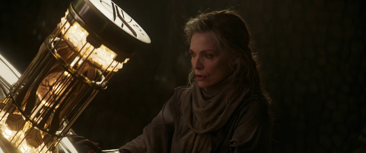 Ant-Man and the Wasp: Quantumania (2023) movie still: medium — A dark, dimly lit chamber contains a complex glowing golden mechanical apparatus. A…