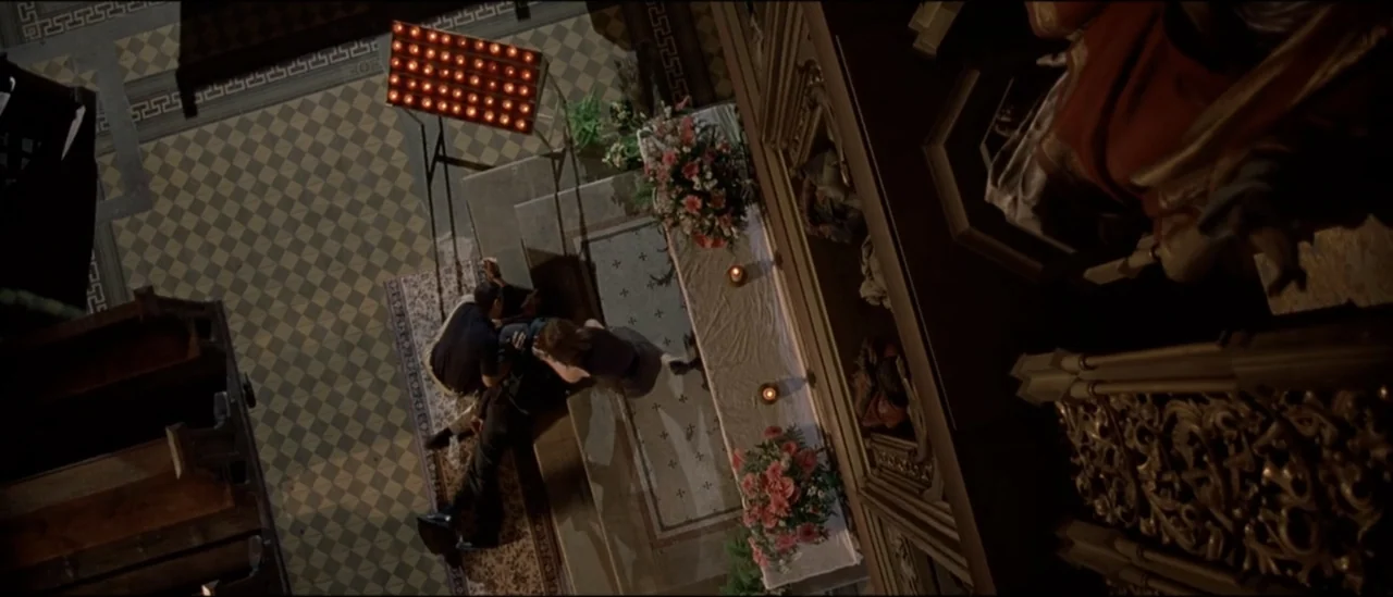 The Peacemaker (1997) movie still: wide — A dark church interior with checkerboard tile flooring and an ornate wooden altar area. Three figures…