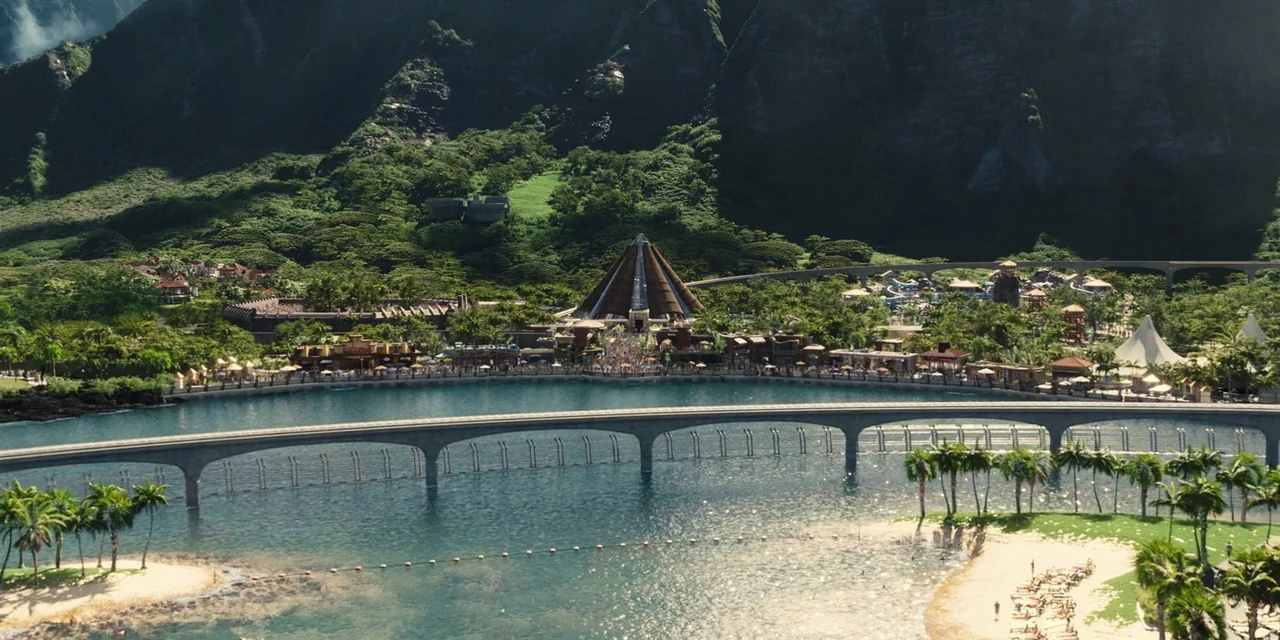 Jurassic World (2015) movie still: establishing — A vast tropical island resort features a large central pyramid structure near water. A long…
