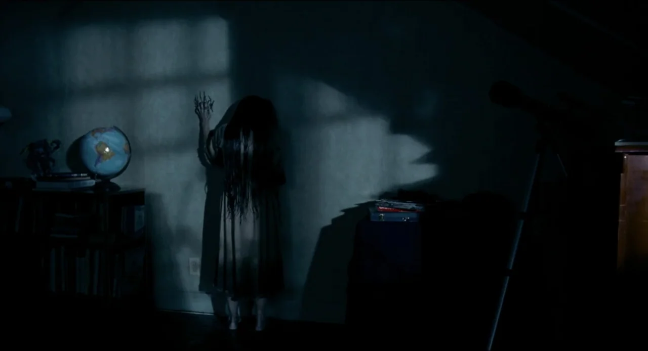 The Ring Two (2005) movie still: fullbody — A dark bedroom contains a bookshelf, a globe, and a tripod-mounted telescope. A young girl with long…