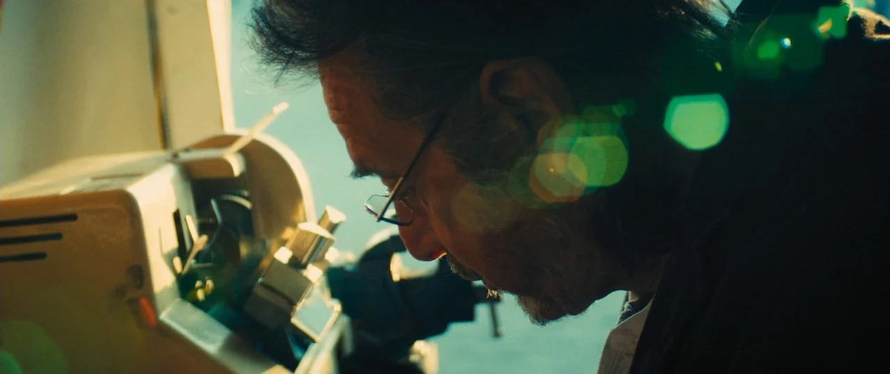 Manglehorn (2014) movie still: closeup — A man works on a mechanical device in a bright, sunlit interior space. The man focuses intently on the…
