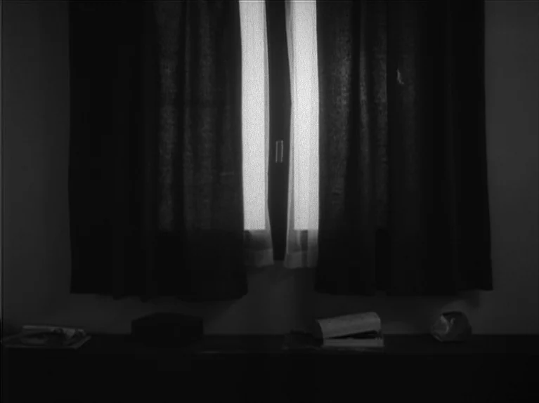 My Night At Maud’s (Ma Nuit Chez Maud) (1969) movie still: medium — A dark room features a window covered by heavy, dark curtains. A shelf holds a…
