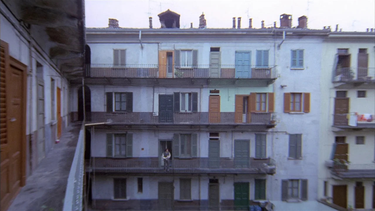 Death Occurred Last Night (1970) movie still: establishing — A multi-story apartment building features exterior balconies and numerous wooden doors…