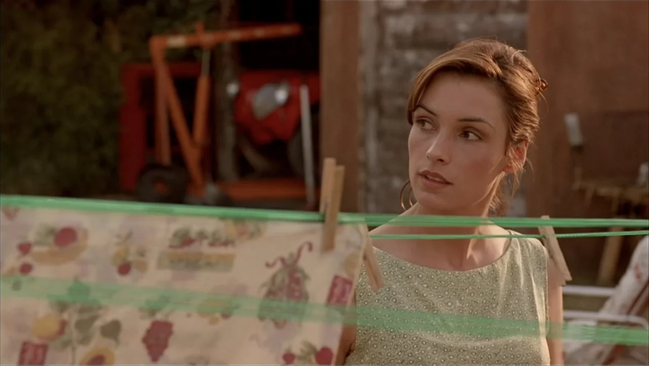 Ajuste de Cuentas (2016) movie still: medium — A backyard setting featuring a clothesline with patterned fabric hanging in the foreground. A woman…