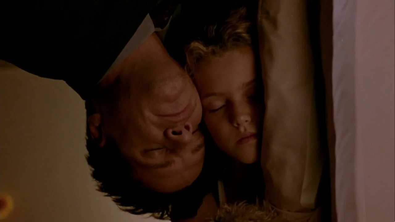Hellraiser: Inferno (2000) movie still: This intimate medium-closeup captures a father and child asleep, their faces nestled closely together in a…