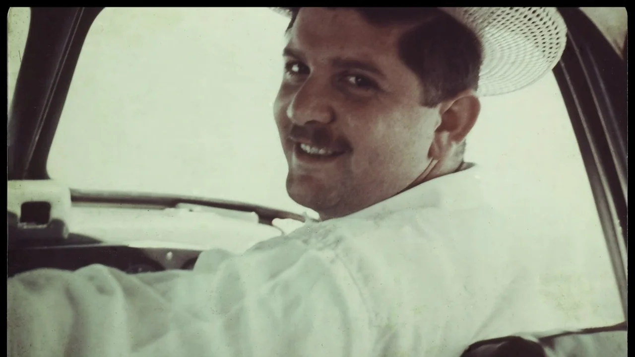 I'm Still Here (2024) movie still: closeup — The interior of an older automobile with visible dashboard edges and textured window frames. A man…