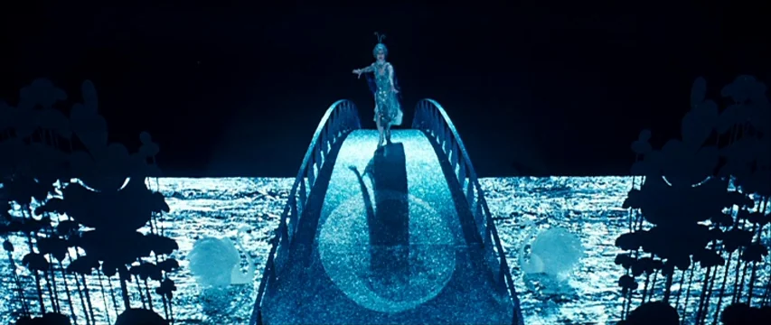 The Boy Friend (1971) movie still: wide — A stylized theatrical set featuring a curved bridge positioned over a reflective water surface. A solitary…