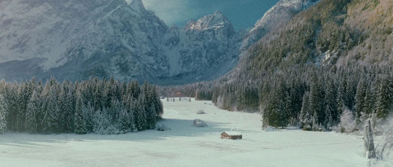 Starfish (2018) movie still: establishing — A wide, snow-covered valley sits nestled between towering, rugged mountain peaks and dense pine forests.…