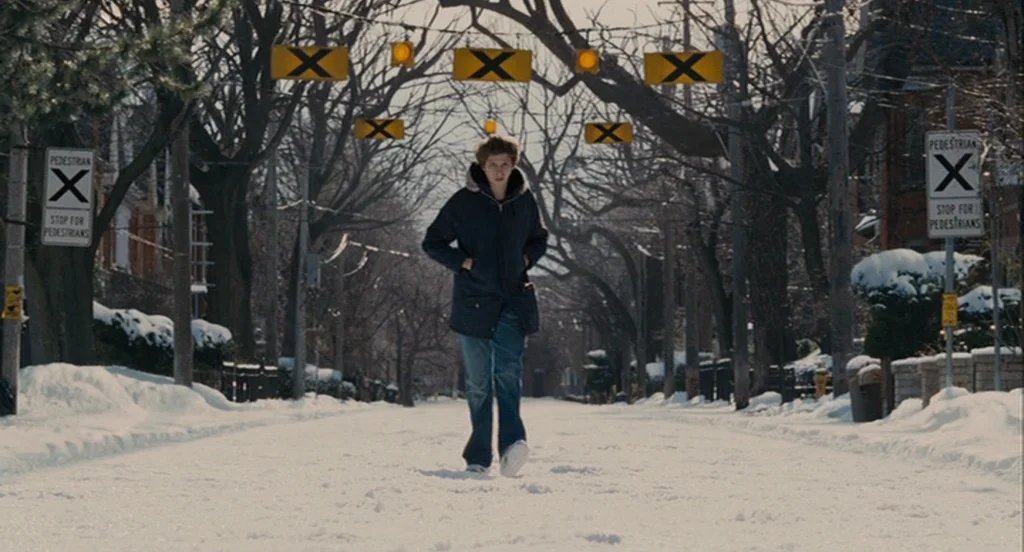 Scott Pilgrim Vs The World (2010) movie still: fullbody — A snow-covered suburban street lined with bare trees and hanging pedestrian warning signs.…