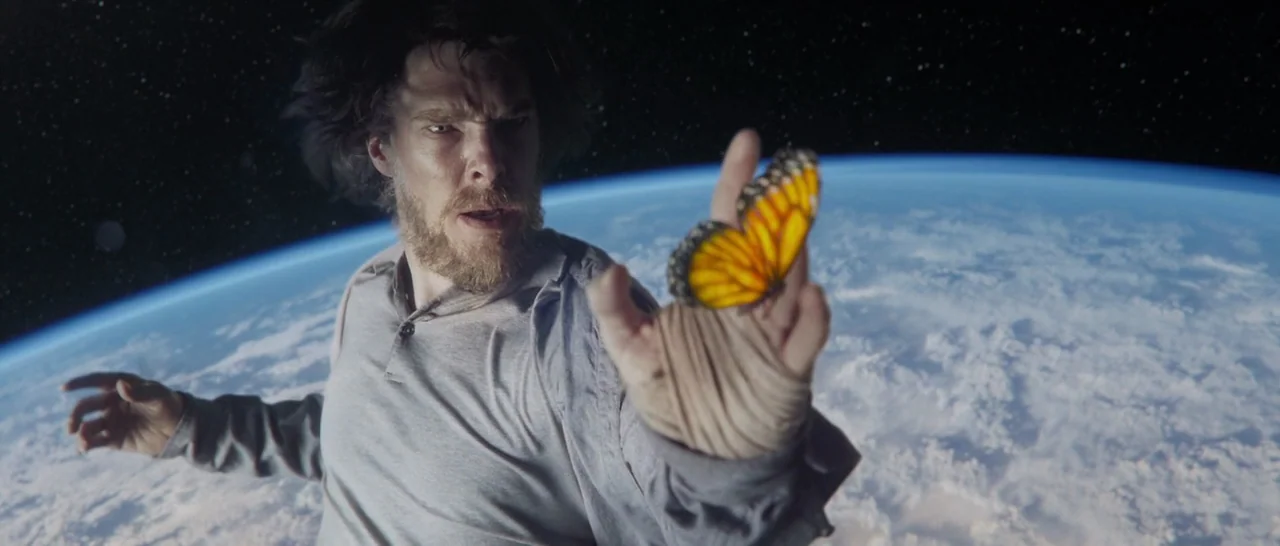 Doctor Strange (2016) movie still: medium — A man drifts in the darkness of outer space above the planet Earth. He watches a monarch butterfly…
