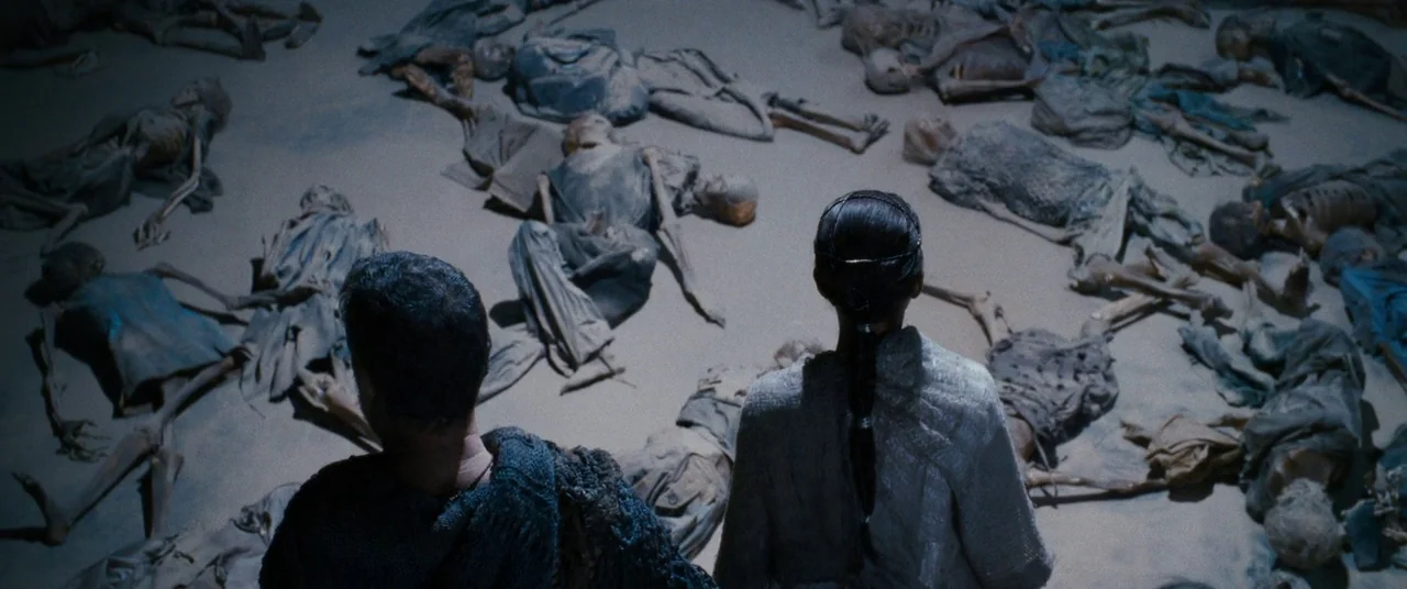 Cloud Atlas (2012) movie still: wide — A vast, barren desert landscape is littered with dozens of scattered, weathered human remains. Two people…