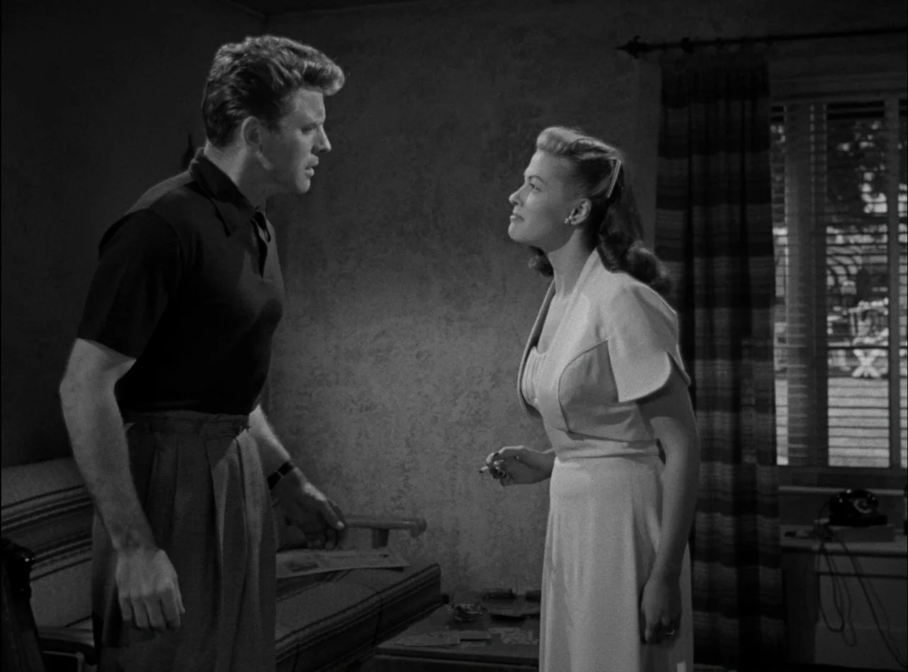 Criss Cross (1949) movie still: medium — A classic interior setting features a man and a woman standing together. They are engaged in a conversation…