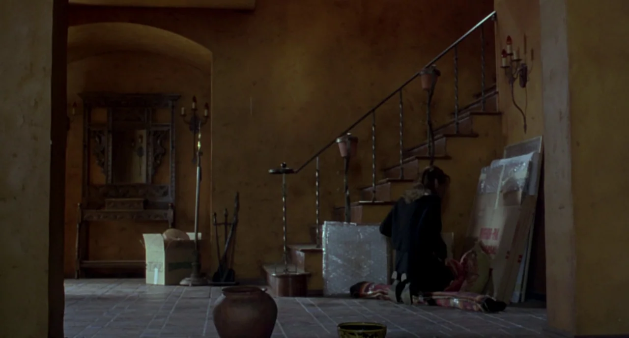 The Craft (1996) movie still: wide — A terracotta-tiled foyer with warm ochre walls features a wooden staircase and antique furnishings. A woman in…
