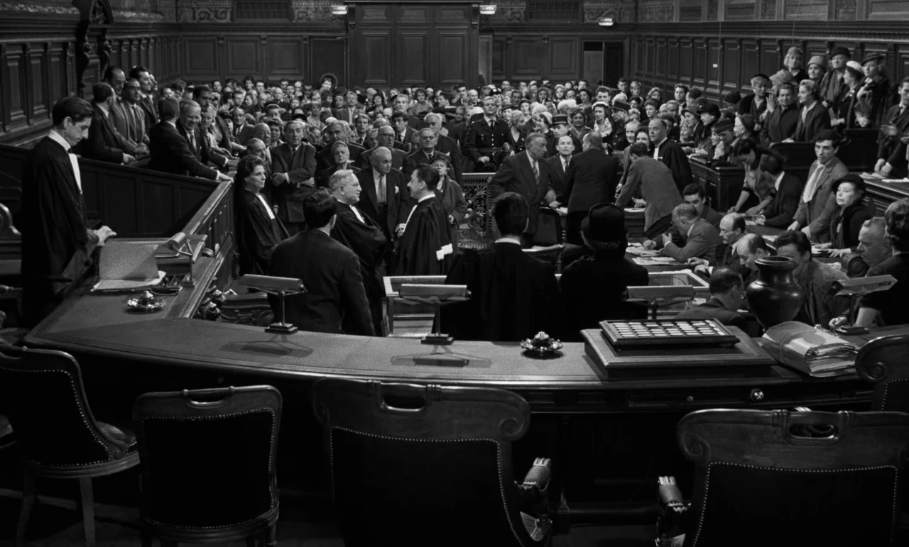 La Verite (1960) movie still: wide — A dense crowd of people in formal attire gathers in a grand wood-paneled courtroom. Lawyers in black robes…