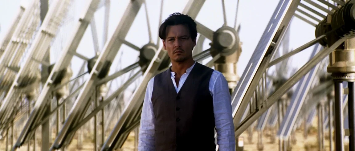 Transcendence (2014) movie still: medium — A field filled with large, angled solar panel structures arranged in symmetrical rows. A man stands…