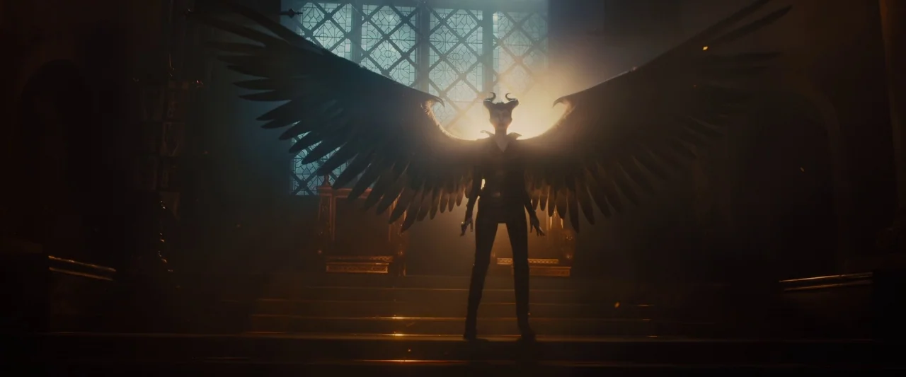 Maleficent (2014) movie still: fullbody — A stone interior space with wide stairs and a large window in the rear. A woman with large black wings…
