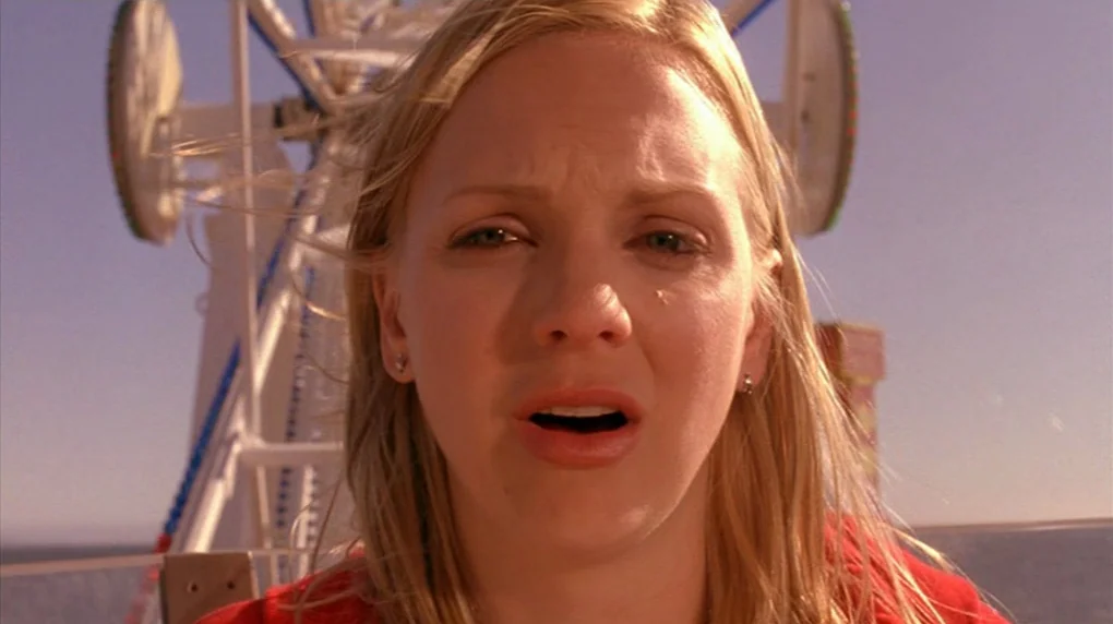 Smiley Face (2007) movie still: closeup — A woman is captured in a close-up against the steel frame of a ferris wheel. She looks ahead directly…