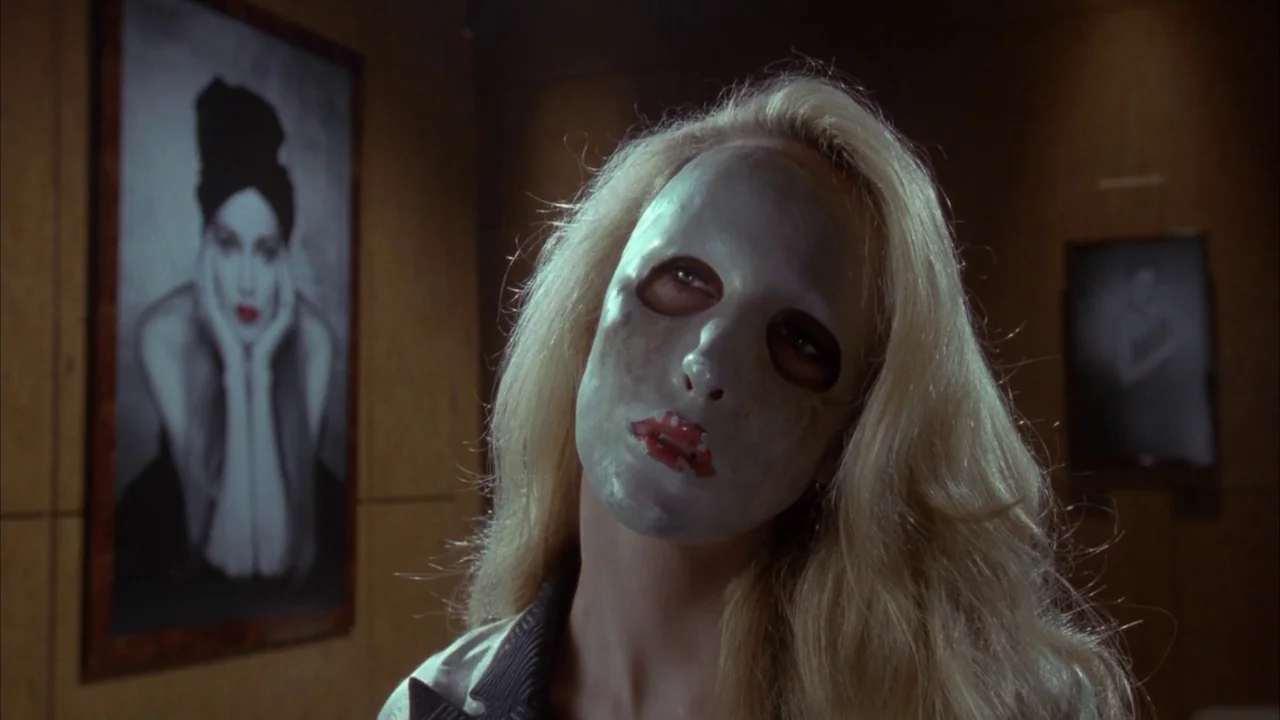 Batman (1989) movie still: closeup — An interior art gallery features a portrait of a woman hanging on wooden walls. A blonde woman wearing a…