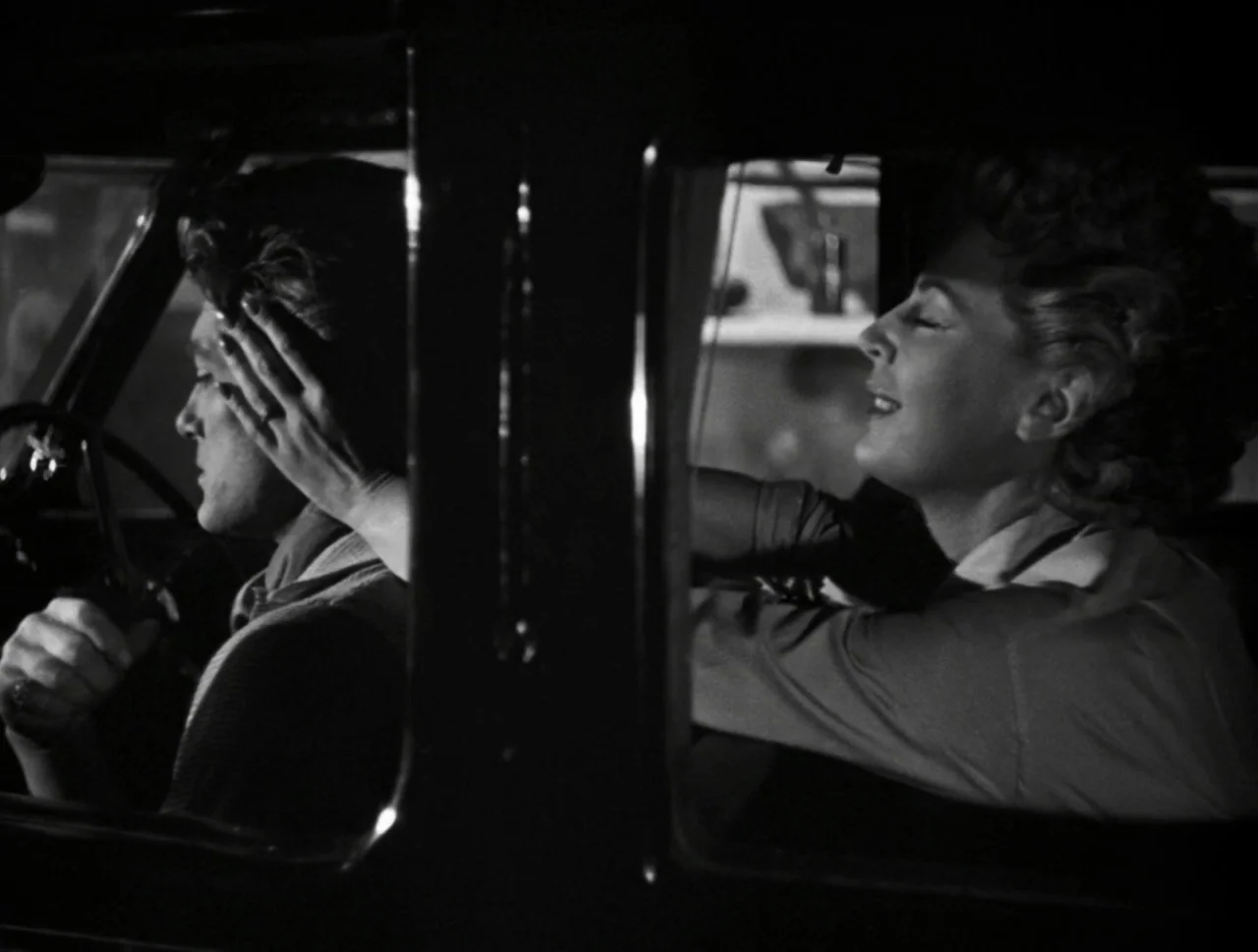 Orpheus (1950) movie still: medium — The interior of a vehicle at night featuring two people side by side. A woman reaches out to touch the side of…