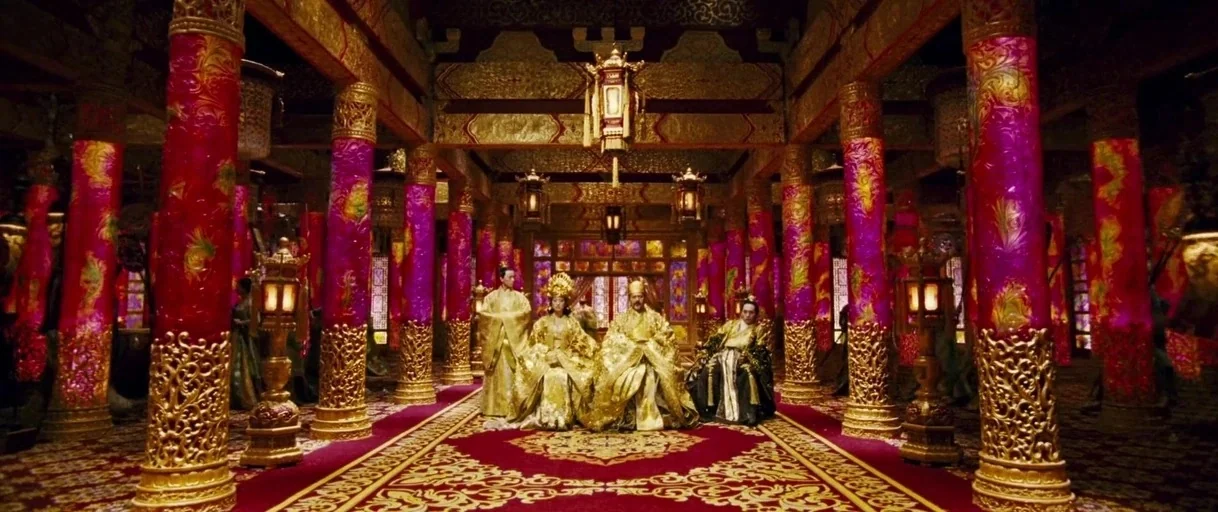 Curse of the Golden Flower (2006) movie still: wide — A vast imperial hall featuring rows of bright magenta columns with intricate gold carvings.…