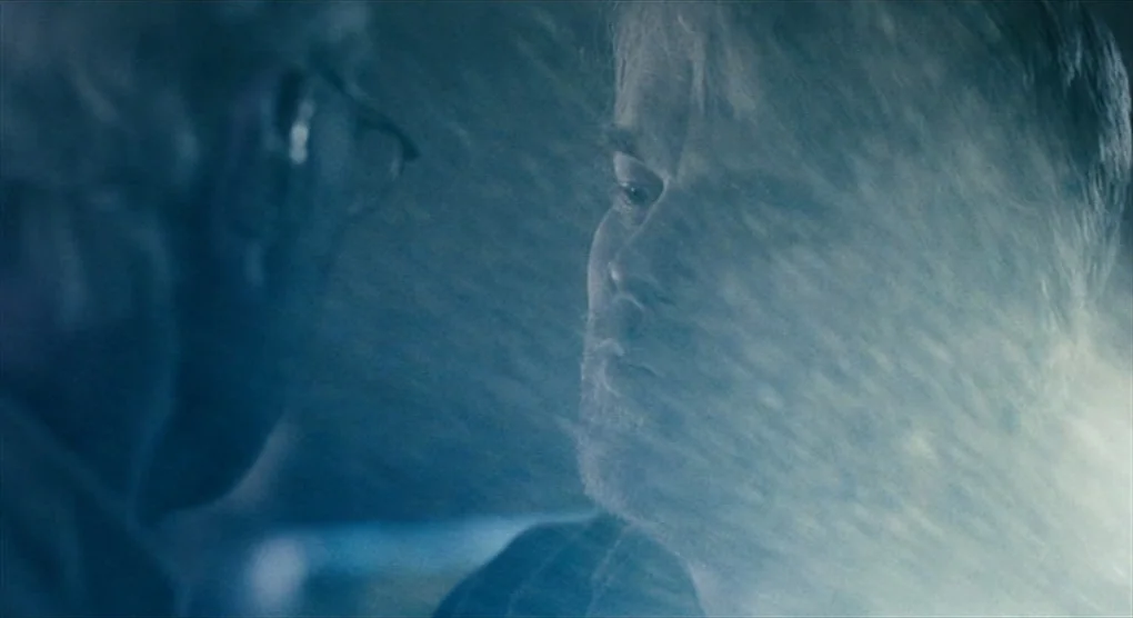 The Savages (2007) movie still: closeup — A dark environment with minimal visible detail aside from two characters close together. One man is…
