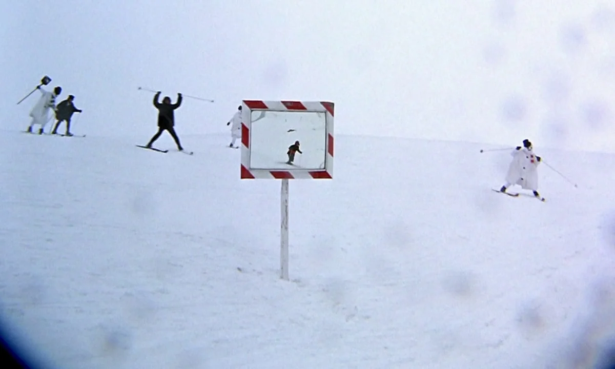 Help! (1965) movie still: wide — A vast, flat, and featureless snow-covered slope extends to a distant horizon line. Multiple figures move across…