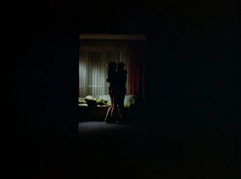 Ali: Fear Eats The Soul (1974) movie still: wide — A dark hotel room interior features a large window with thin curtains and red drapes. A couple…